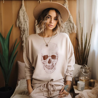 Beige long sleeve graphic top featuring a bold skull design on the front with a relaxed boutique casual silhouette.