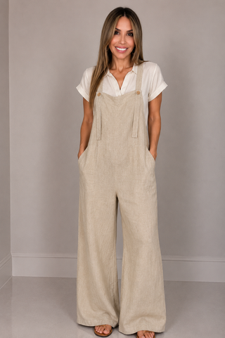 Sand beige linen wide leg jumpsuit with adjustable straps and front pockets for a relaxed warm-weather outfit.
