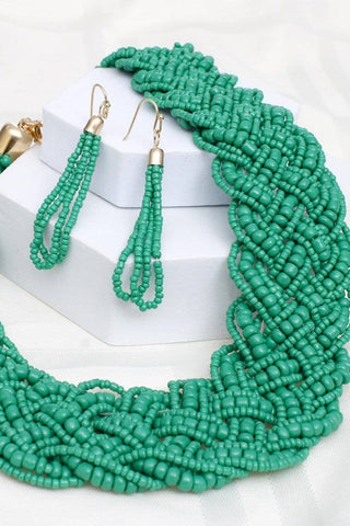 Green beaded necklace and earrings on a white background