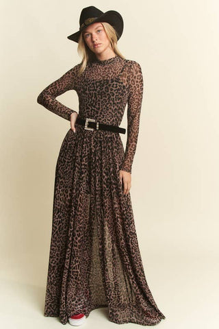 Woman wearing a long leopard print dress with a black belt and hat on a beige background