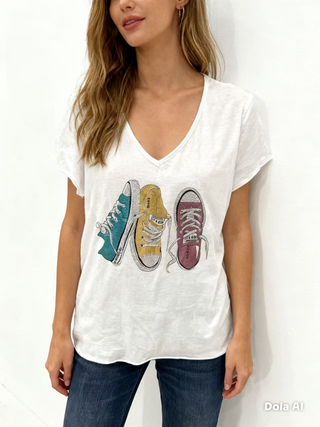 White V-neck graphic tee with short sleeves and a multicolor sneaker print in teal, mustard, and burgundy.
