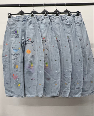 Light wash wide leg jeans with colorful cherry, cocktail, fruit, and doodle graphics displayed on hangers.