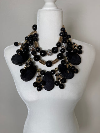 Layered black statement necklace set with glossy beads, gold-toned accents, crystal details, and dramatic teardrop embellishments.