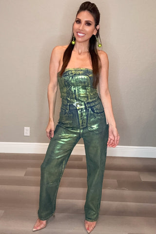 Woman wearing a green metallic jumpsuit standing in a room with a neutral background.