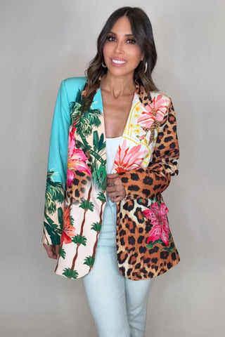 Woman wearing a colorful jacket with floral and leopard print patterns on a plain background