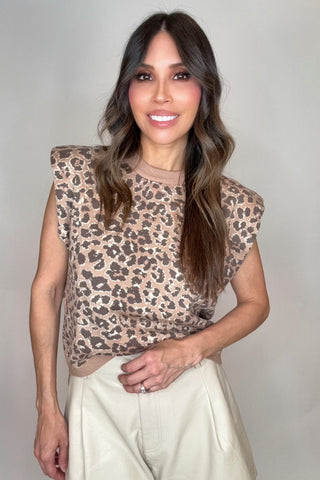 Woman wearing a leopard print top and light-colored pants against a plain background