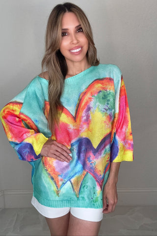 Lightweight Italian knit top with a relaxed draped silhouette and vivid multicolor watercolor painted heart graphic.