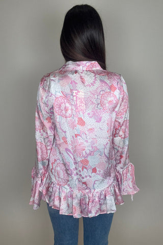 Person wearing a pink floral dress with ruffles on a plain background