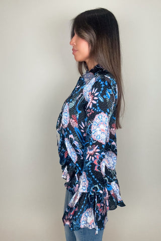 Woman wearing a long-sleeve floral blouse against a plain background