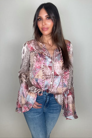 Woman wearing a patterned blouse and jeans against a plain background