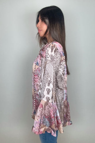 Woman wearing a patterned long-sleeve top against a plain background