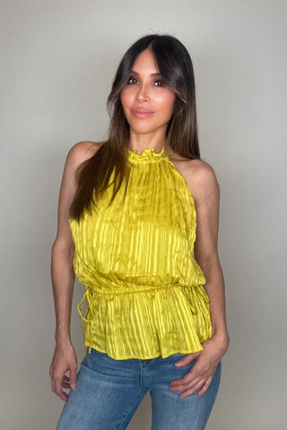 Woman wearing a yellow top and blue jeans against a plain background