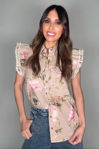Woman wearing a floral blouse with ruffled sleeves against a plain background