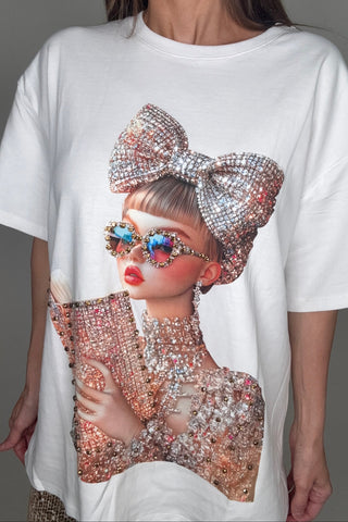 Person wearing a white outfit with a large decorative bow and colorful earrings on a gray background