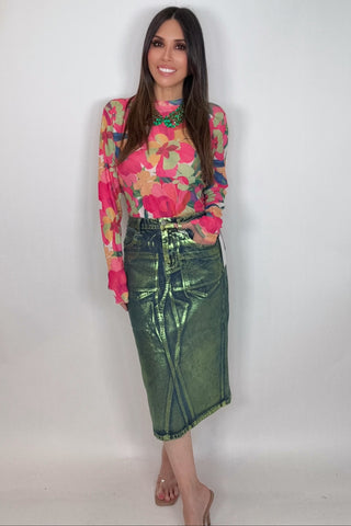 Woman wearing a colorful floral top and green skirt against a white background