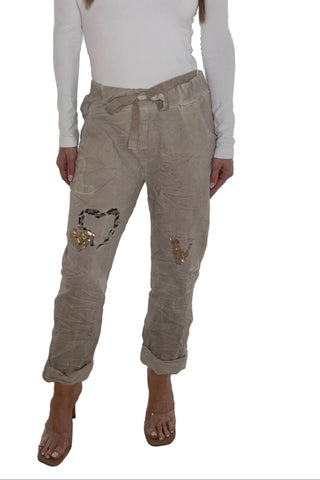Taupe joggers with gold sequin heart patches and leopard print trim, relaxed fit and rolled cuffs.