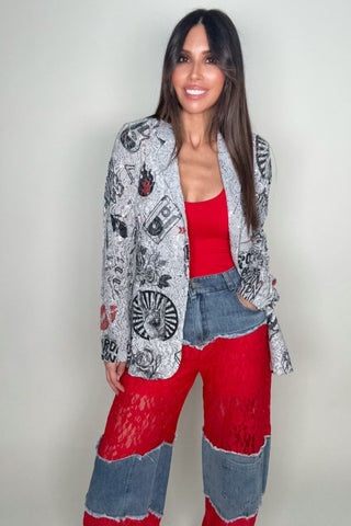 Woman wearing a patterned cardigan, red top, and colorful pants against a plain background