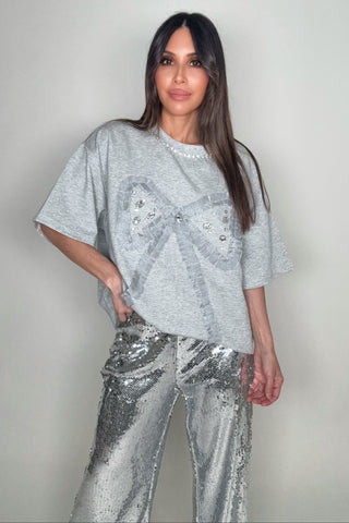 Woman wearing a silver sequin outfit against a plain background