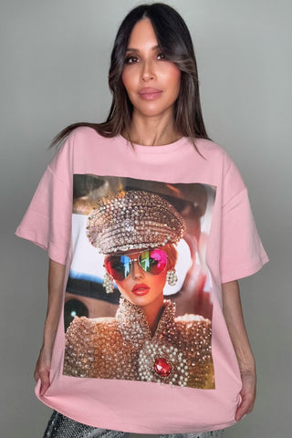 Person wearing a pink t-shirt with a graphic design of a person in a rhinestone outfit.