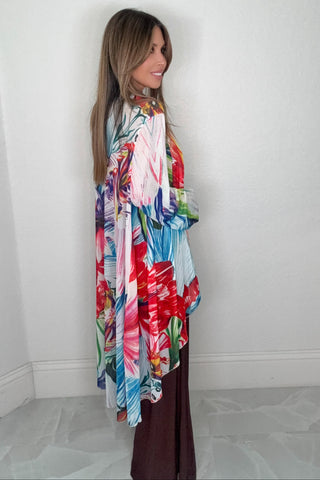 Floral multicolor mesh duster jacket with an open front, longline silhouette, vibrant floral print, and ruffled hem.