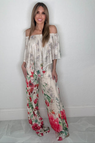 White sleeveless jumpsuit with a V-neckline, floral mesh overlay, and flowy wide-leg pants.