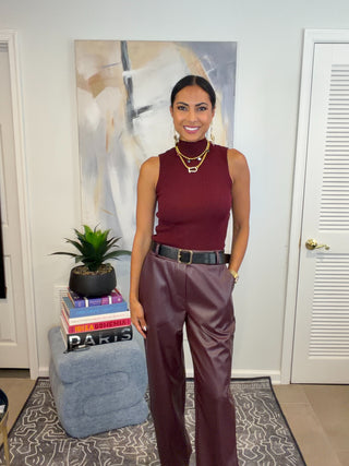 Burgundy faux leather straight leg pants with a high waist, black belt, gold buckle and side pockets.