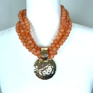 Coral beaded layered necklace with gold-tone chains and a hammered round pendant.