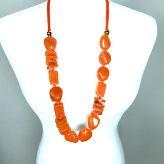 Orange long beaded necklace with chunky varied geometric beads styled as a vibrant statement accessory.