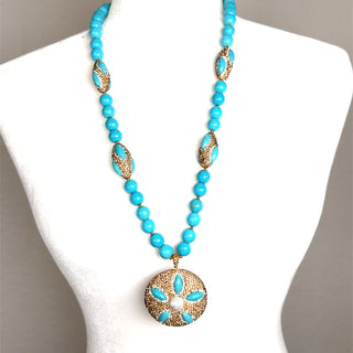 Long turquoise beaded necklace with gold crystal accents and an ornate round medallion pendant.