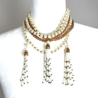 Layered pearl statement necklace with gold-tone chain accents and tassel pendants cascading at the front.