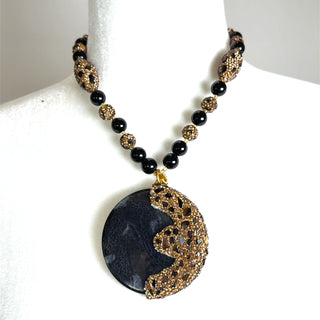 Black gemstone gold crystal necklace with a large round pendant and textured gold beading for an elegant statement jewelry look.