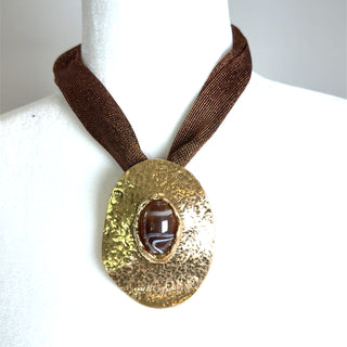 Brown metallic gold pendant necklace with a hammered gold tone pendant, centered brown cabochon accent, and mesh brown chain.