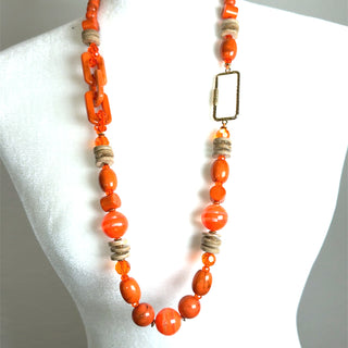 Long strand necklace with vibrant orange wooden beads, natural beige accent beads, and asymmetrical hardware.