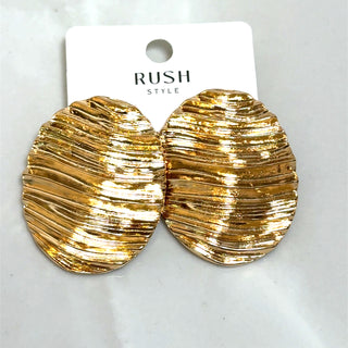 Pair of oversized gold textured wave statement earrings with sculpted, radiant finish displayed on a white jewelry card.