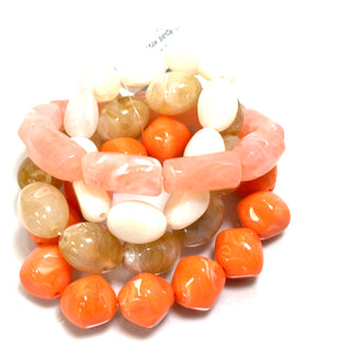 Coral-toned bracelet stack with gold accent details styled as a bright boutique accessory.