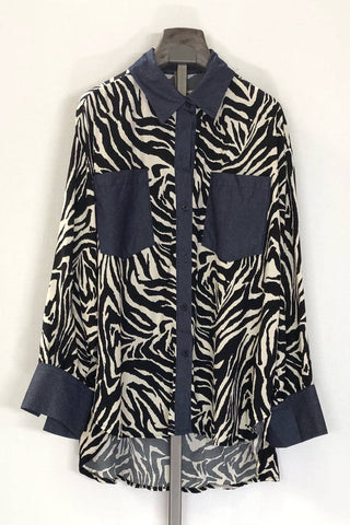 Zebra pattern shirt with navy accents on a hanger against a white background