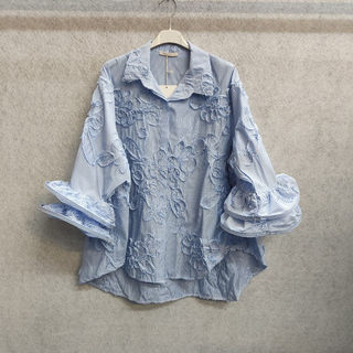 Italian denim button down top with pinstripe texture, dimensional rosette applique, long cuffed sleeves, and a relaxed high-low hem.