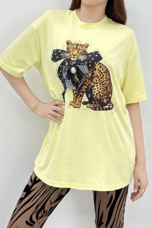 Woman wearing an oversized butter yellow graphic tee with a leopard design and 3D bow embellishment, styled with animal print leggings.
